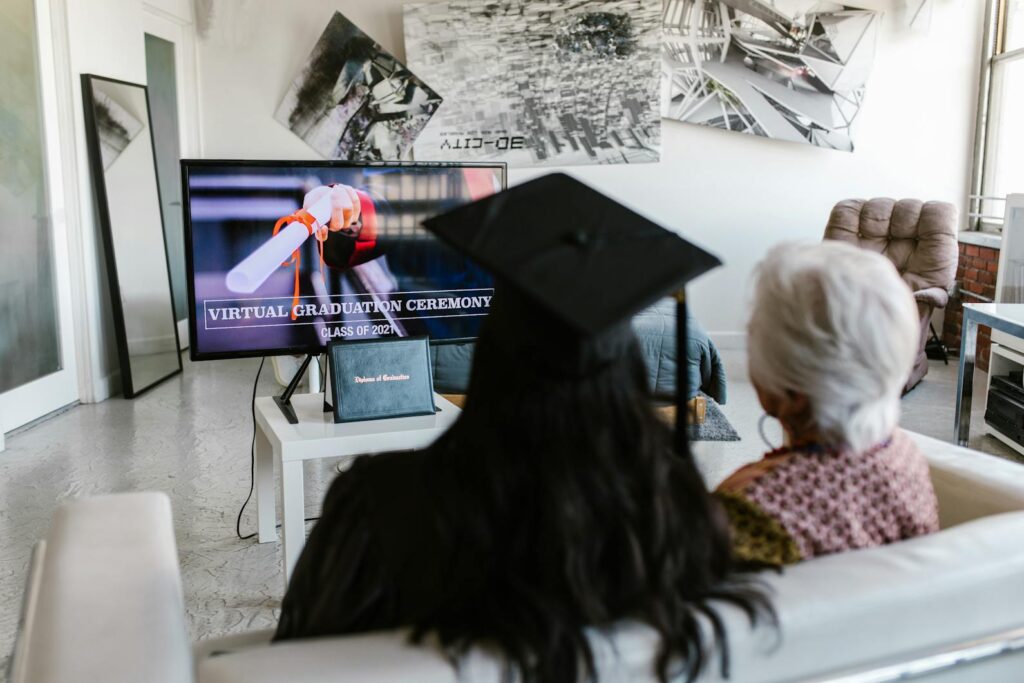 A Person Wearing Graduation Cap Attending Virtual Graduation Ceremony with an Elderly